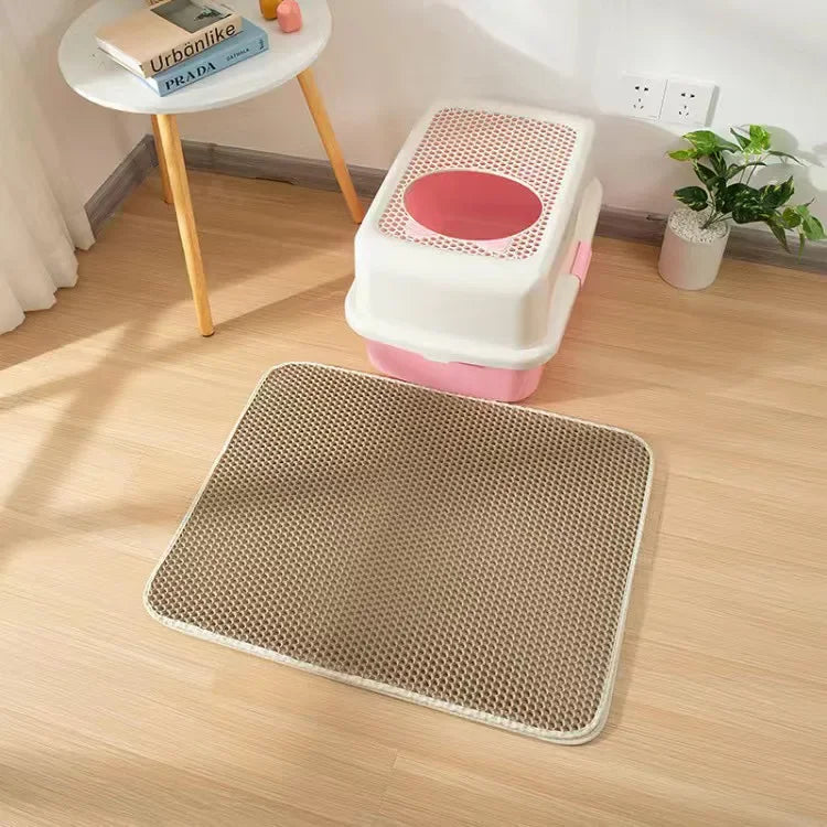 Cat litter box with a mat on a wooden floor in a room setting.