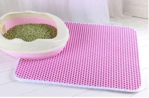 Cat litter box with a pink litter mat on a white floor